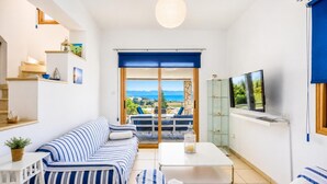 A modern living room with a sofa, coffee table, and TV, with a view of the sea and mountains. - Argaka Sunset Villa - Three Bedroom Villa, Sleeps 6 (Argaka)
