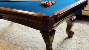 Una mesa de billar con estructura de madera y una alfombra estampada.
