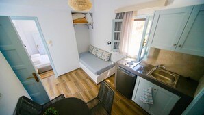 A compact kitchen with a built-in dishwasher, a small dining table, and a bench with cushions.