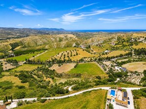 Paisaje rural con una casa que cuenta con piscina, paneles solares y un camino que la lleva a ella.