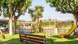 A park with a bench, playground equipment, and a yellow slide. - Residential Costamar Playa, with swimming pools near Bcn (Cabrera de Mar)