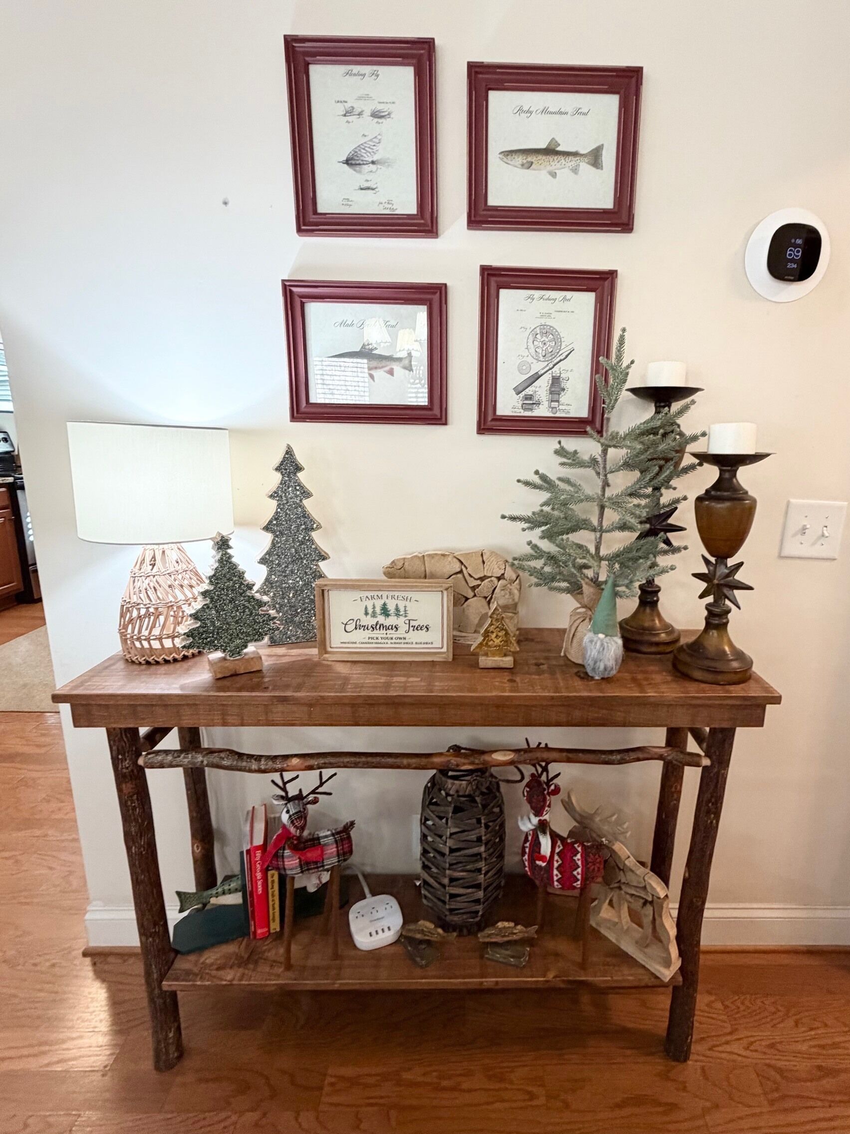 A wooden table with framed fish illustrations, a Christmas tree, and a sign for farm-fresh Christmas trees.