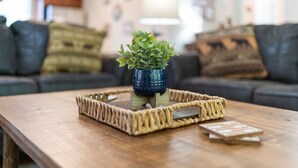 Una mesa de centro de madera con una bandeja tejida que contiene una pequeña planta en maceta y un objeto decorativo.