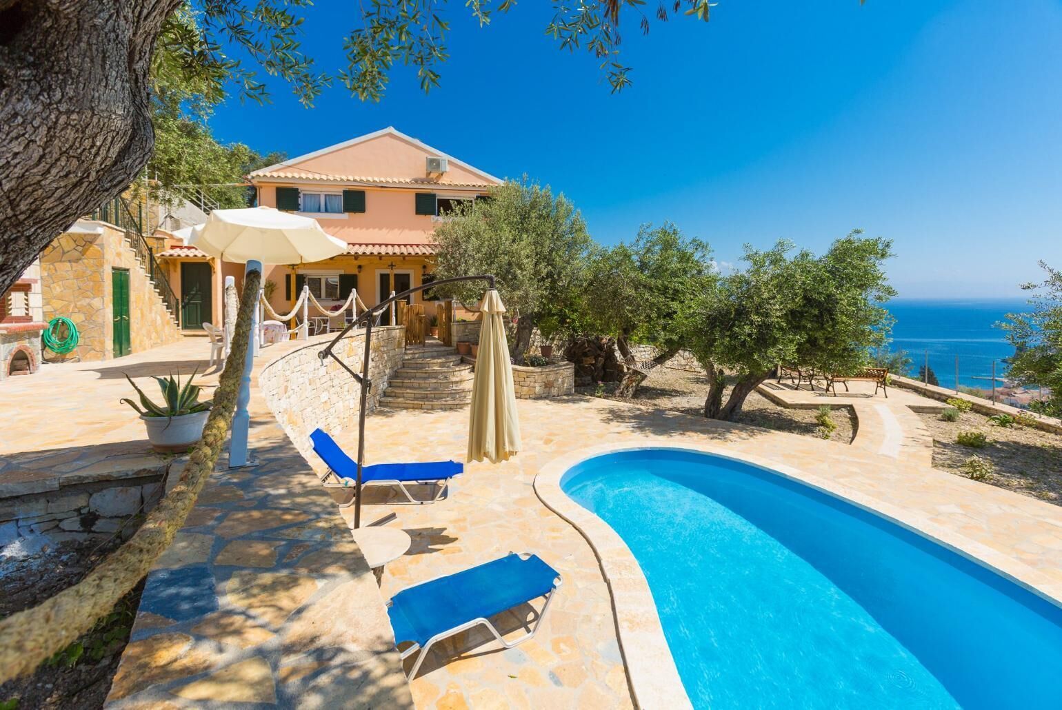 Un'area piscina con una piscina a forma di curva, sedie a sdraio e vista sul mare.