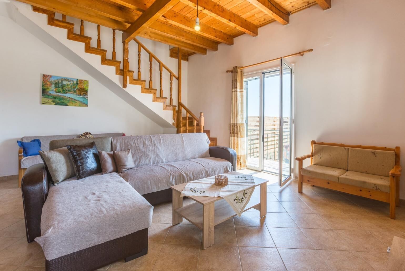 Un salon spacieux avec un escalier en bois, un canapé, une table basse et un balcon offrant une vue dégagée.