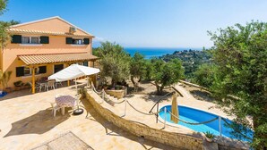 Ein zweistöckiges Haus mit Pool, Sitzgelegenheit im Freien und Meerblick.