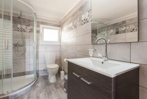 A modern bathroom with a glass shower enclosure, a toilet, and a vanity with a sink and mirror. - Villa Francesca - Two Bedroom Villa, Sleeps 4 (Paxi)