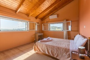 A bedroom with a bed, a nightstand, a mirror, an air conditioning unit, and a window with a view of the outdoors. - Villa Francesca - Two Bedroom Villa, Sleeps 4 (Paxi)