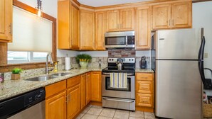 Una cocina con gabinetes de madera, un refrigerador de acero inoxidable, un microondas, un horno y un lavavajillas.