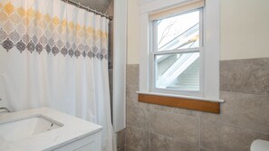 A bathroom with a shower curtain, a window, and a sink.
