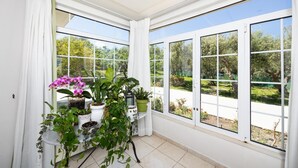 A room with large windows, a potted plant arrangement, and a view of greenery outside. - Villa Armi - Four Bedroom Villa, Sleeps 8 (Pirgos)