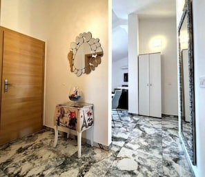 Experience a clean and functional space with a wooden door, a small table, and a decorative mirror.