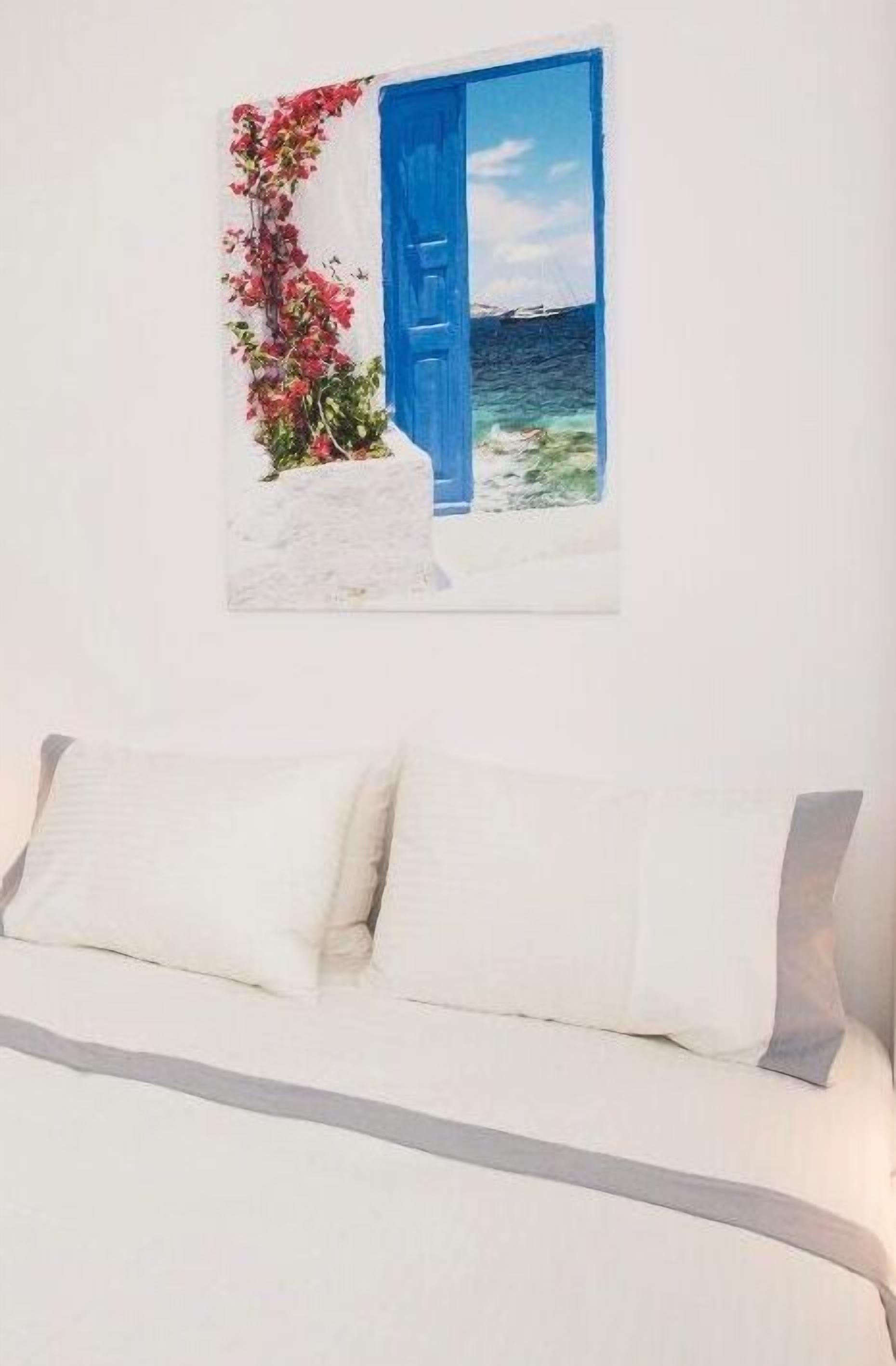 Cama com roupa de cama branca e um travesseiro, porta pintada de azul e parede branca.