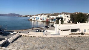 A coastal town with white buildings, a stone-paved area, and a clear blue sky. - Christy Suites by Alpha Living (Mykonos)