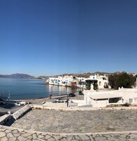 Un pueblo costero con edificios blancos, un cielo azul despejado y un mar tranquilo.