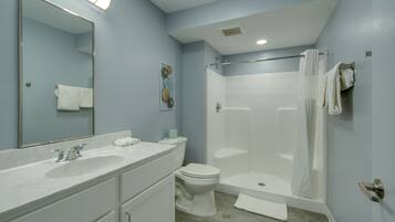A bathroom with a large mirror, two sinks, a toilet, and a walk-in shower.