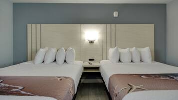 A hotel room with two beds, a nightstand, and a wall-mounted light fixture.