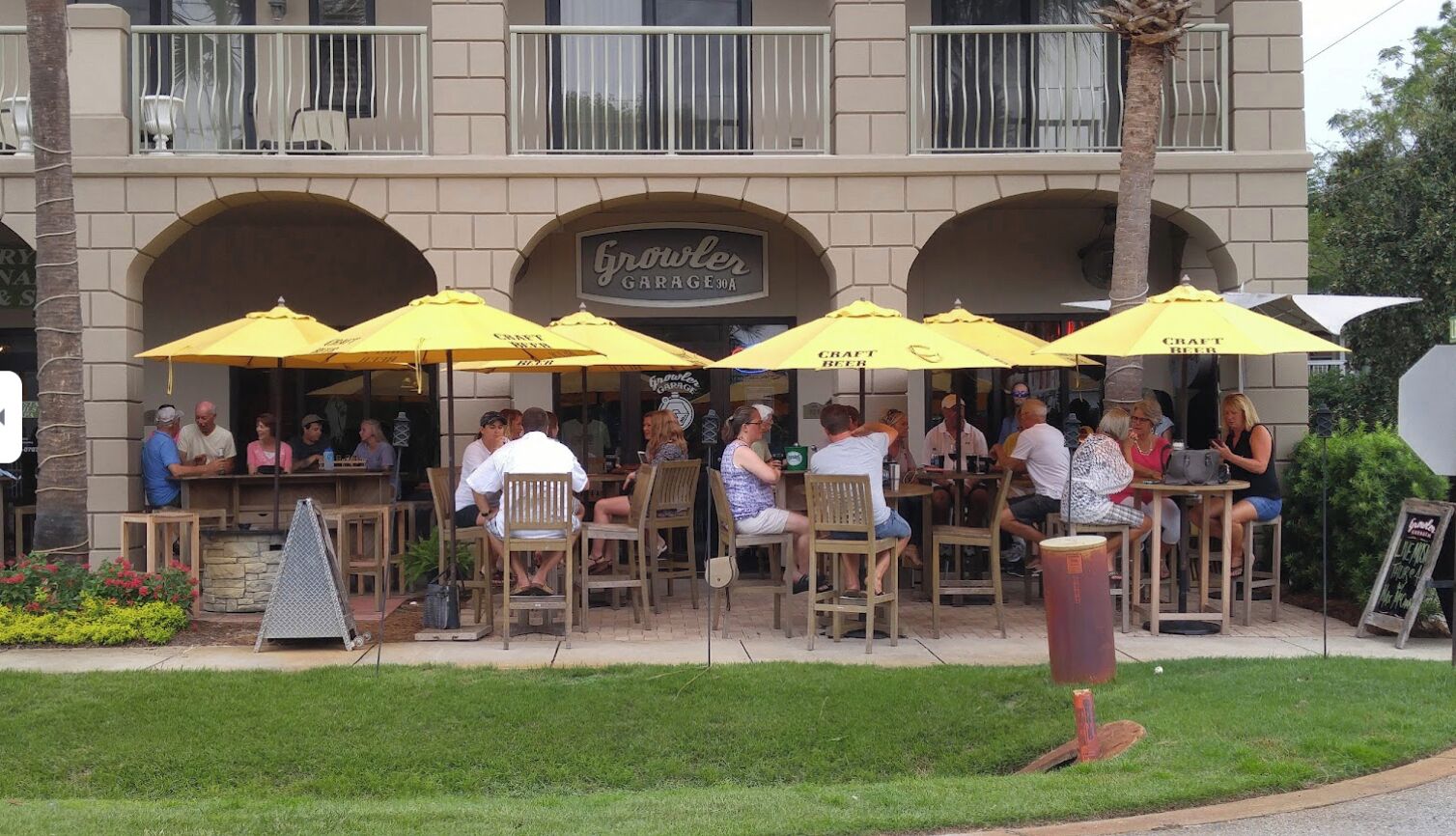 An outdoor seating area with yellow umbrellas at a restaurant named 'Growler Garage'.