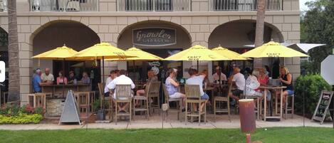 An outdoor seating area with yellow umbrellas at a restaurant named 'Growler Garage'.
