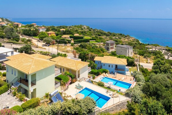 A coastal residential area with houses, a swimming pool, and a view of the sea.