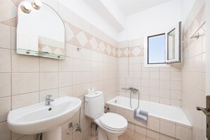 Un baño con lavamanos, inodoro y bañera.