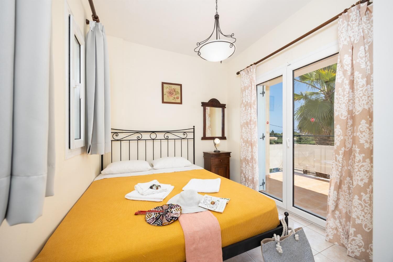 Une chambre à coucher avec un lit, une table de chevet, un miroir et une vue sur l’extérieur.