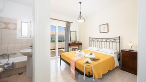 Ein Hotelzimmer mit Bett, Nachttisch, Bad mit Waschbecken und Toilette sowie einer Glastür zum Balkon.