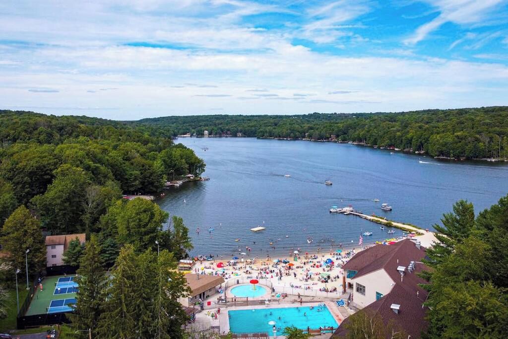 A lakeside resort with a swimming pool, tennis courts, and a beach area.