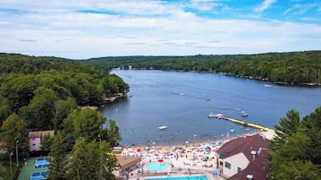 A lakeside resort with a swimming pool, tennis courts, and a beach area.