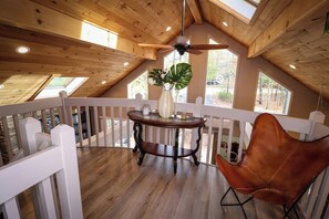 Eine Holzterrasse mit Tisch und Stühlen, einem Deckenventilator und Blick ins Freie.