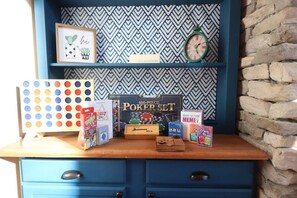 Un bureau en bois avec un bloc de tiroirs bleu, un tableau encadré, une horloge et divers jeux de société.