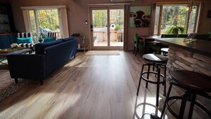 Un ambiente acogedor con sofá, comedor y ventanas amplias que ofrecen vistas al exterior.