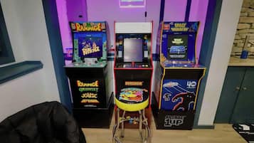 Spelautomater, en pall och en neonreklamskylt i ett rum.