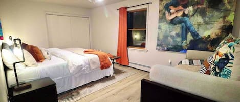 A bedroom with two beds, a ceiling fan, a large painting, and a window with curtains.