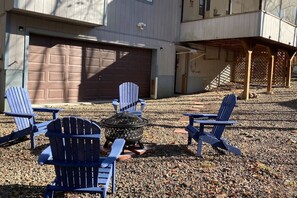 Un jardin avec des fauteuils Adirondack, un foyer extérieur et un espace patio couvert.
