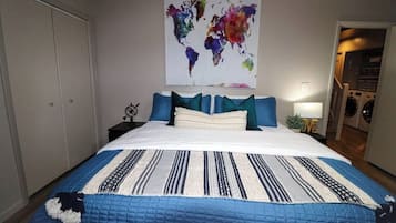 A bedroom with a bed, pillows, a world map artwork, a nightstand, and a lamp.