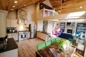 A spacious kitchen with a dining area, a loft bedroom, and a living room with a fireplace.