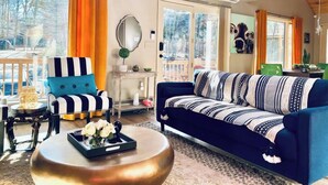 Un salon spacieux avec un canapé bleu, un fauteuil à rayures et une table basse ronde.