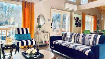 Un salon spacieux avec un canapé bleu, un fauteuil à rayures et une table basse ronde.