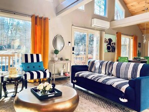 Ein geräumiges Wohnzimmer mit einem blauen Sofa, einem gestreiften Sessel und einem runden Couchtisch.