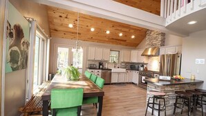 Una cocina espaciosa con vigas de madera en el techo, armarios blancos y una isla central con taburetes.