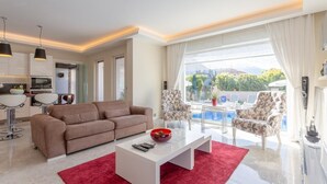 Ein modernes Wohnzimmer mit einer Couch, einem Couchtisch und Blick auf einen Pool.