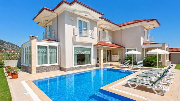 Ein zweistöckiges Haus mit Swimmingpool, Sitzgelegenheiten im Freien und Blick auf die umliegende Landschaft.