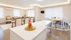 Un vaste espace de vie comprenant une table à manger, un canapé et un téléviseur fixé au mur.