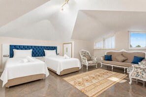 Ein Schlafzimmer mit zwei Betten, einem Schlafsofa, einem Sessel und einem großen Fenster.