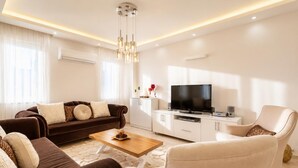 Uma sala de estar moderna com sofá, poltrona, mesa de centro, TV e armários embutidos.