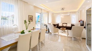 Uma sala de estar moderna com área de jantar, sofás e televisão.