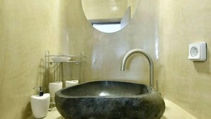 A bathroom with a large stone sink, a mirror, and a towel rack. - Casterly Rock by Alpha Living (Mykonos)