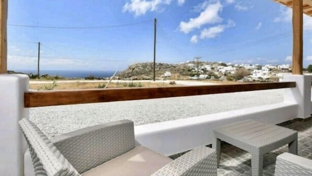 A covered outdoor seating area with a view of a coastal town and the sea. - Casterly Rock by Alpha Living (Mykonos)