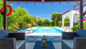A pool area with wicker furniture, a lantern, and a clear blue sky. - Sun Beach Villa Thio (Poli Crysochous)